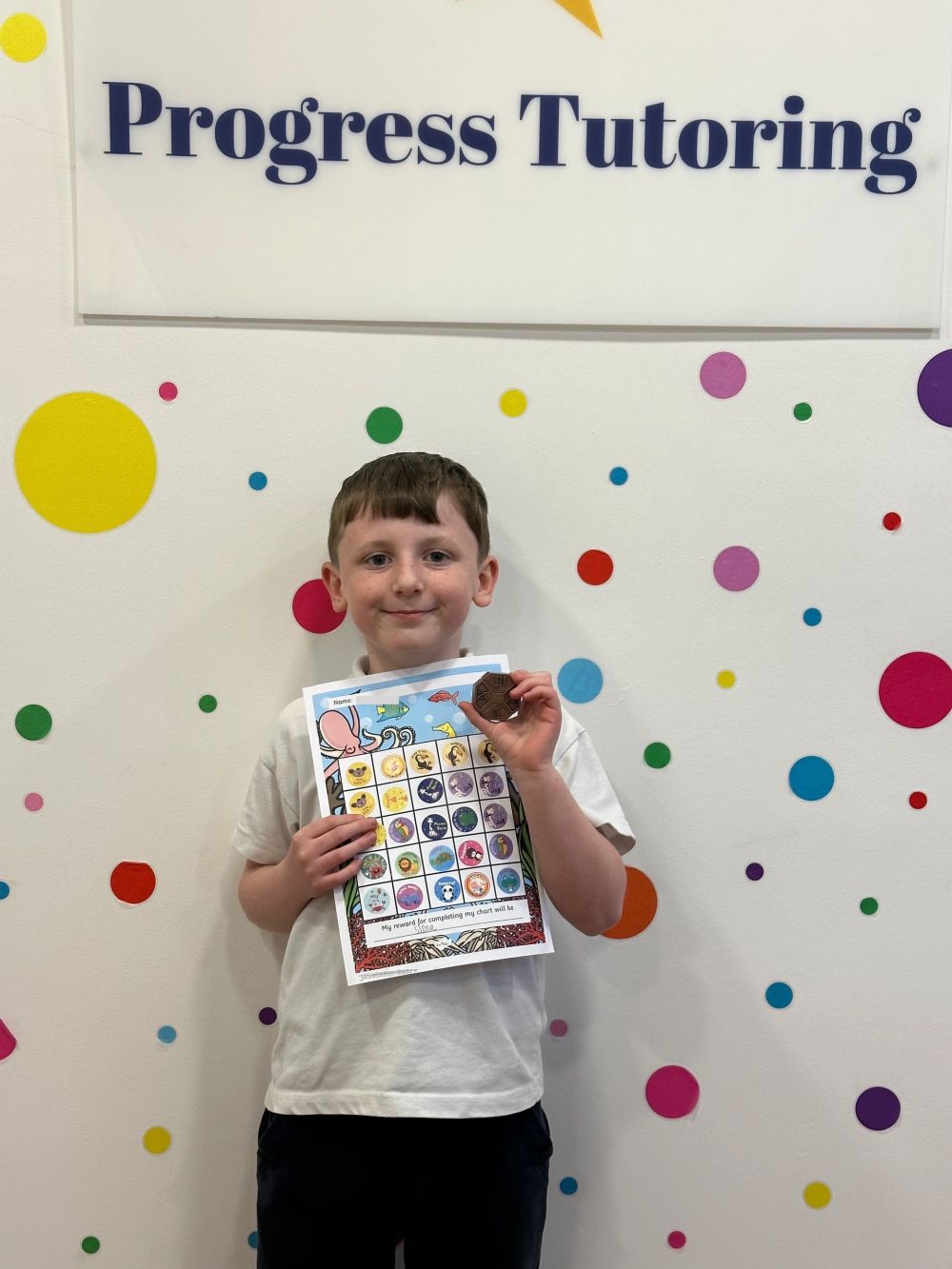 A Progress Tutoring primary pupil celebrating their completed reward chart
